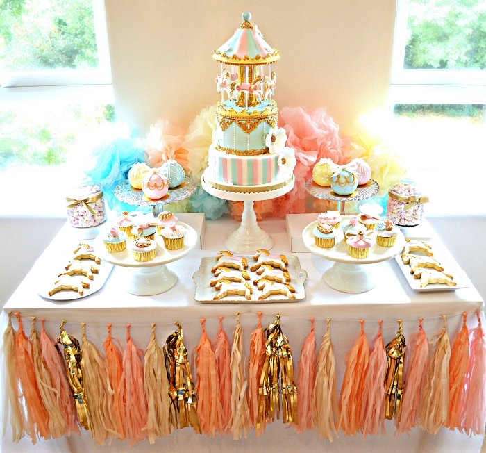 jolie déco de table sur le theme anniversaire carrousel, candy bar d'anniversaire décoré d'une guirlande tassels en rose, or et pêche
