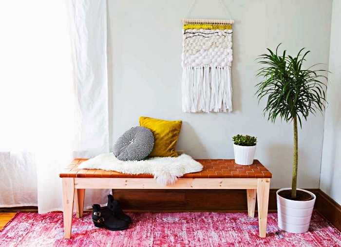 petit hall d'entrée de style bohème chic avec banc en bois et cuir, une tapisserie murale et un tapis rose fuchsia effet délavé