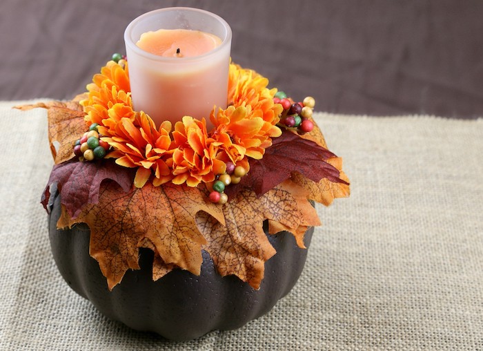 idee deco table automne avec une citrouille repeinte de peinture marron avec deco de feuilles d automne et fleurs orange et bougie au centre