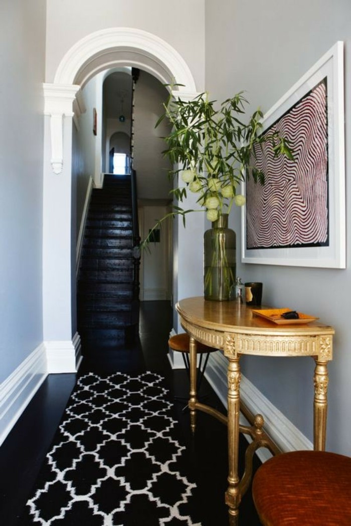 Noir sol et murs gris, meuble étroit couloir, décoration simple et efficace, vase avec fleurs sur table semi ronde