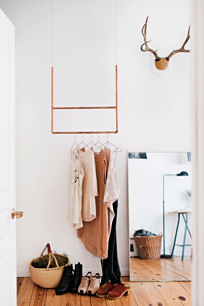 coin dressing avec penderie minimaliste en cuivre suspendue au plafond et un grand miroir rectangulaire posé contre le mur