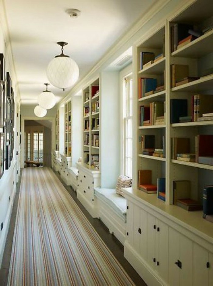Étagères ouvertes avec beaucoup de livres, tapis long, vestiaire étroit de couloir, belle décoration entrée chic