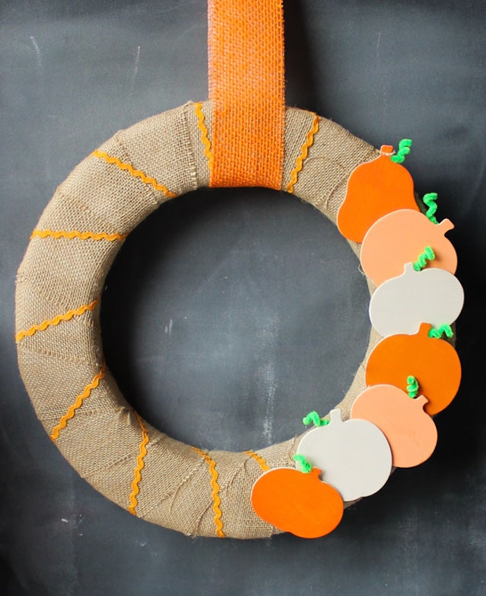 modele de couronne automne en cercle de mousse décoré de bande de jute avec deco de figurines de citrouilles en bois avec suspension sur bande de jute orange