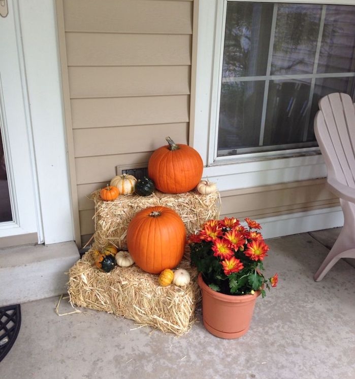 deco entree maison pour l automne avec des bottes de foin, potirons et citrouilles de tailles et couelurs variées, fleurs d automne