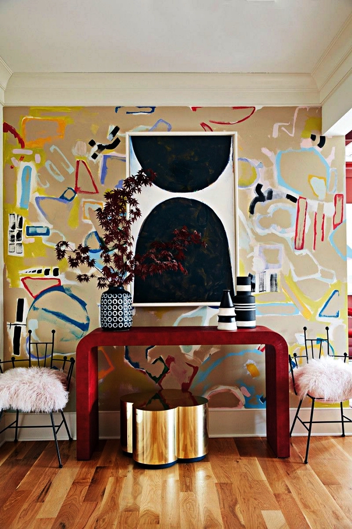 decoration maison moderne, entrée chic avec console design rouge, tabouret en laiton et un mur au papier peint graphique et coloré