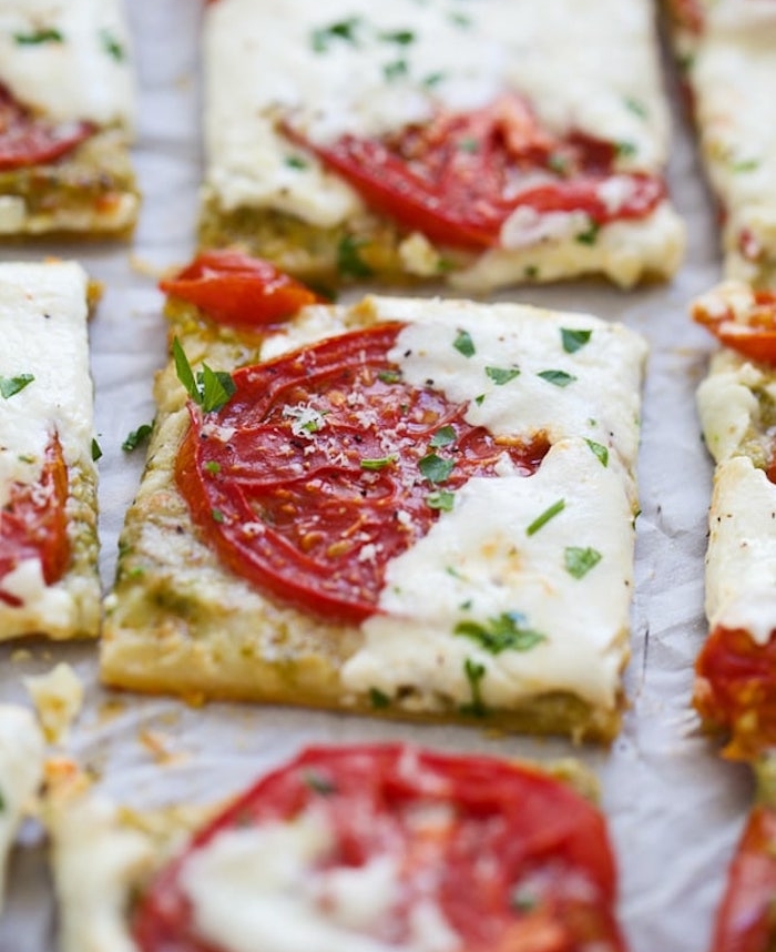 apero dinatoire idee facile, carrés de feuilleté avec tranches de tomate, fromage et persil haché en top