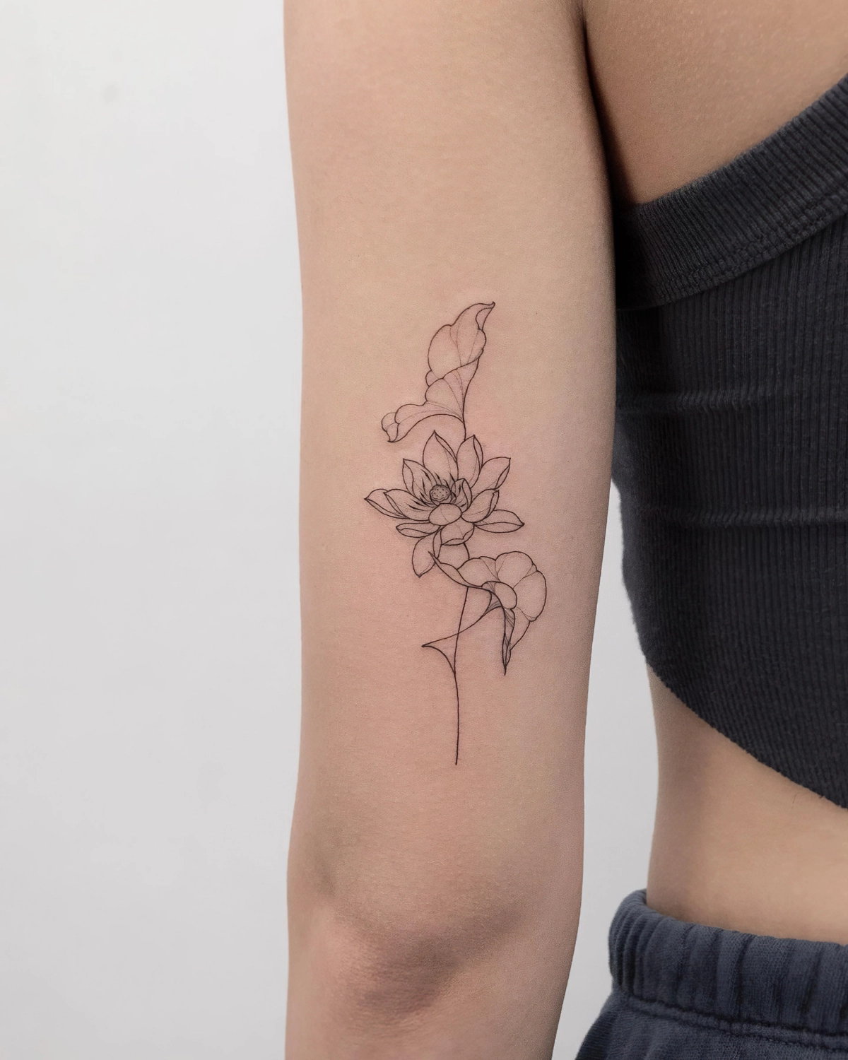 fleur lotus sur tige art corps avant bras tattoo femme debardeur noir