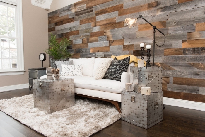 salon cozy avec plancher bois foncé couvert de tapis moelleux blanc et mur habillée en planches bois gris et marron