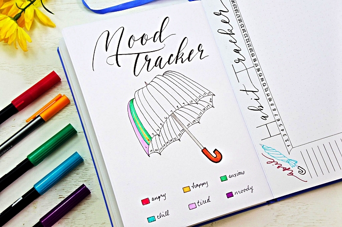 bullet journal tracker sous forme de parapluie avec code couleur, une page avec suivi d'humeurs et titre en calligraphie