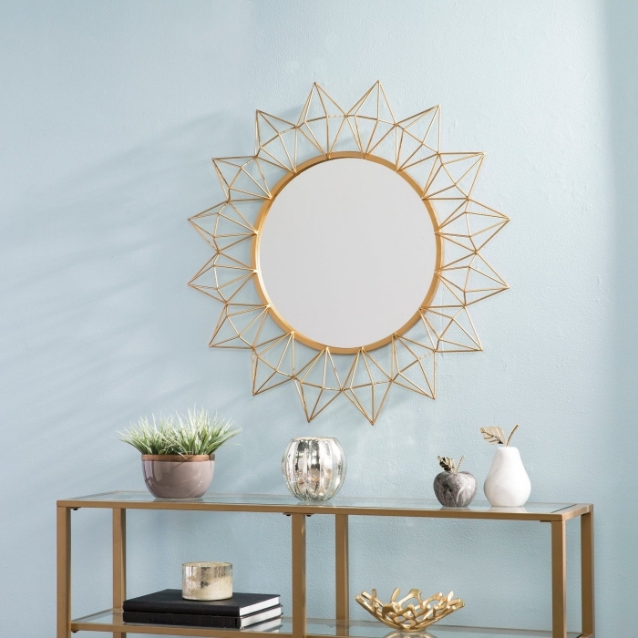 modèle de miroir doré en forme soleil, décoration salon aux murs bleu pastel avec meubles et objets à finition or