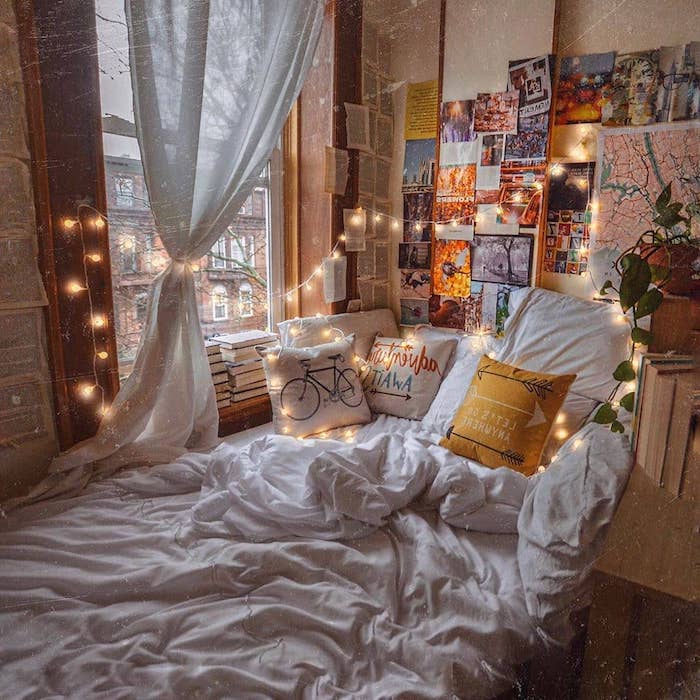 deco chambre de reve avec un lit cosy surchargé de coussins, deco murale de photos et pages de livre, guirlande lumineuse interieur