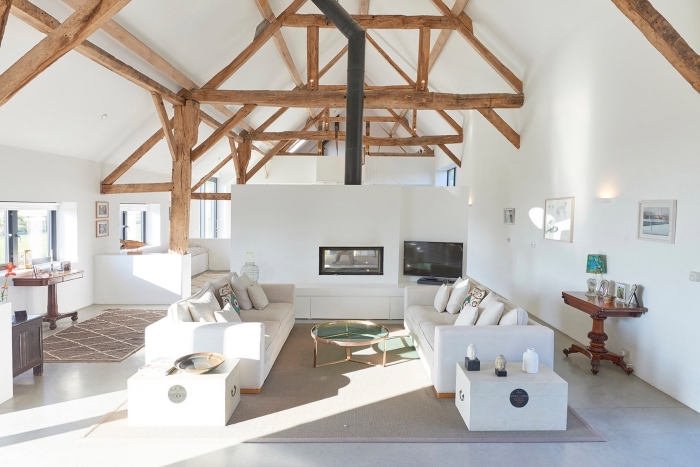 design intérieur minimaliste en blanc et bois, idée aménagement grange en salon loft avec poutres bois apparentes