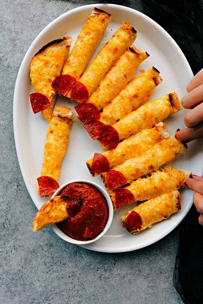 recette halloween horible, bâtonnets de pain au fromage et salami façon doigts servis avec sauce tomate