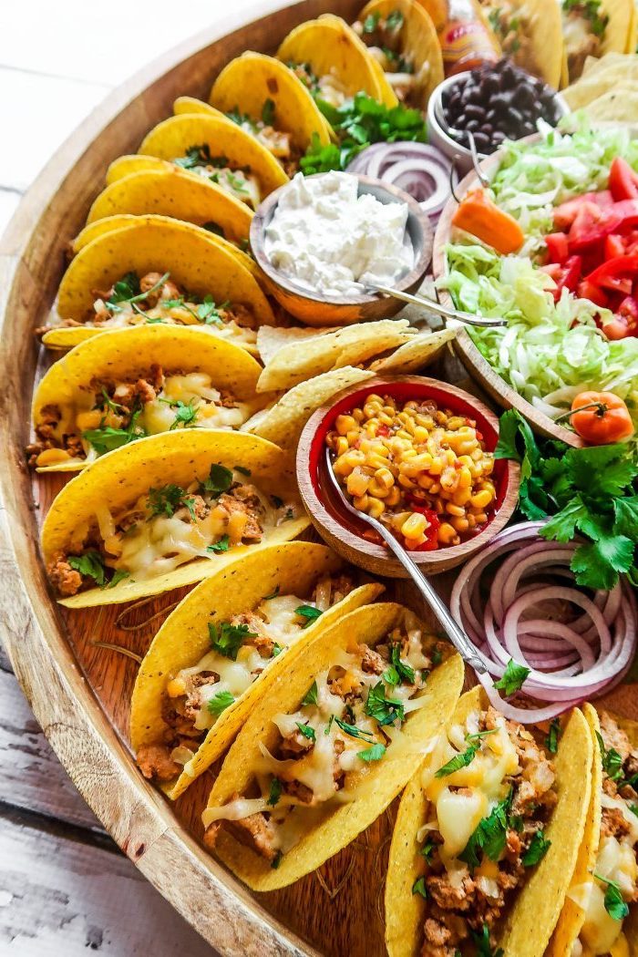 mini-tacos apéritifs au poulet, fromage frais et persil haché, plateau avec bouchées de tacos, sauces et salades diverses