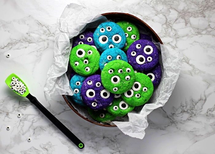 biscuits sablés colorés en vert, bleu et violet au décor de bonbons yeux en sucre, recette halloween originale de petites friandises