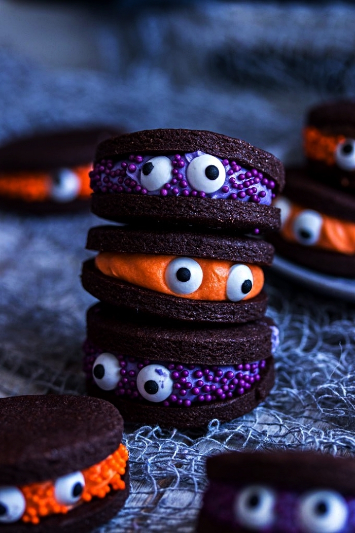 biscuits sandwichs petits monstres d'halloween au chocolat et glaçage coloré orange ou violet, recette halloween de friandises effrayantes