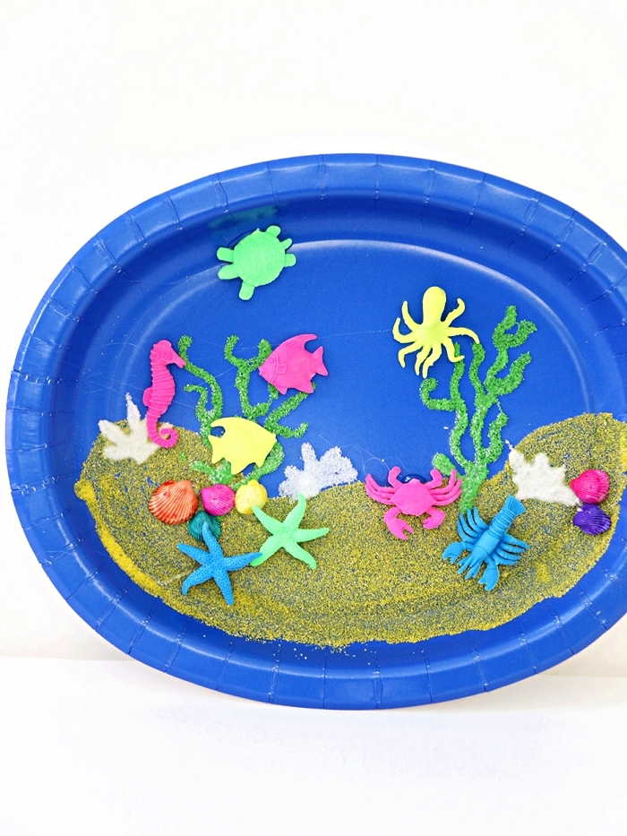 activité manuelle maternelle sur le thème de l'été, fabriquer un aquarium en assiette plastique décorée de sable