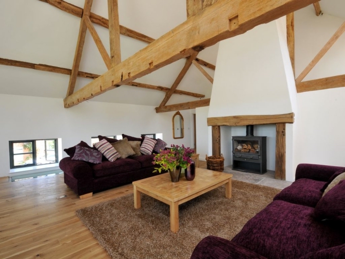 idée transformation grange en habitation, décoration salon rustique avec cheminée, meubles canapés tissu violet foncé