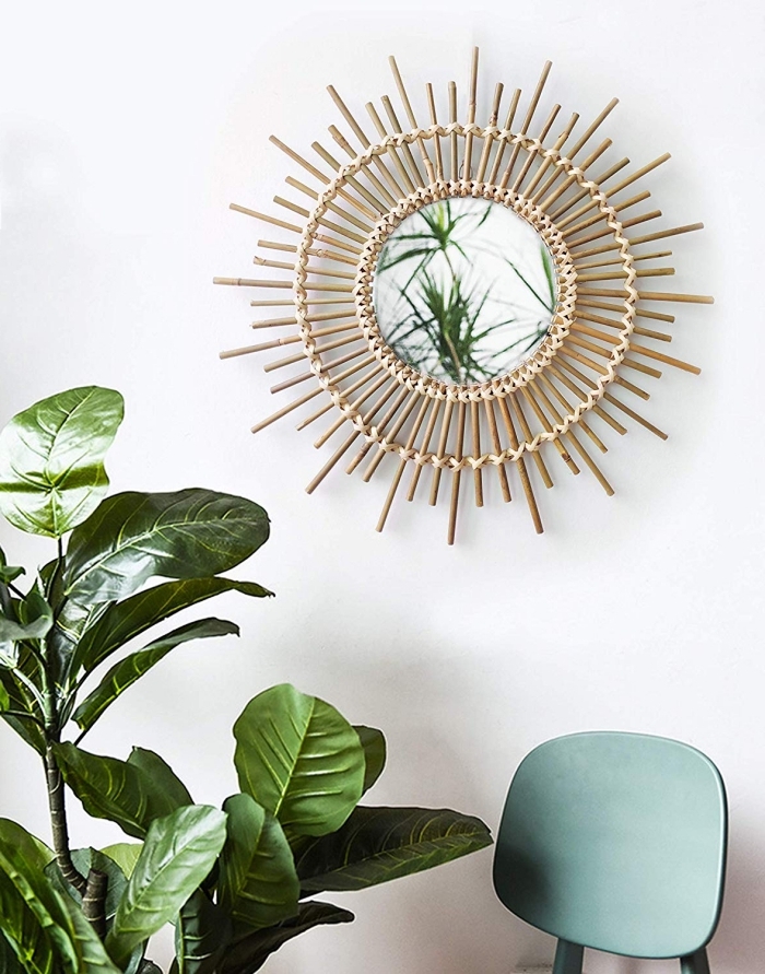 modèle de miroir rotin dans une pièce aux murs blancs avec meubles chaise vert pastel et plantes d'intérieur