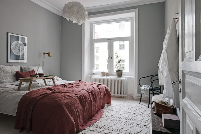décoration chambre à coucher scandinave en gris et blanc, couverture de lit rouge, tapis tricot, suspension blanche, parquet bois clair