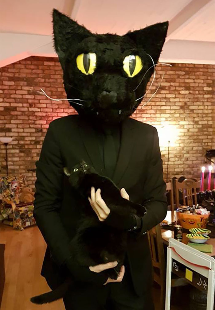 Se déguiser comme son chat noir, le chat sur la photo avec l'homme en son costume noire avec masque de chat noir