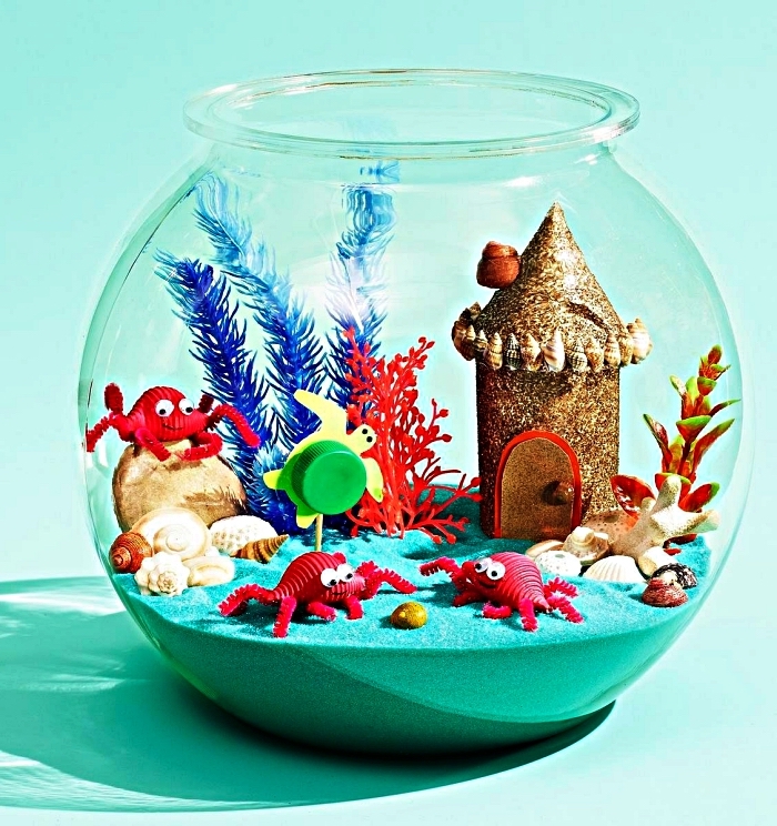 activité manuelle été sur le thème de la mer, aquarium marin avec un fond de sable bleu et des figurines d'animaux marins