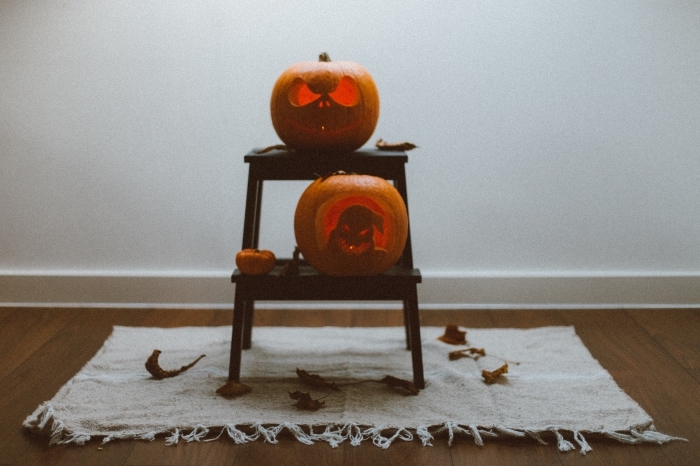 décoration-pour-fête-octobre-photo-halloween-petite-table-bois-en-miniature-tapis-avec-franges-feuilles-séchées-citrouilles diy décor pour halloween avec citrouilles jack'o, idée citrouille halloween sculptée posée sur table bois basse