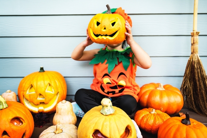 déguisement-enfant-en-citrouille-halloween-décoration-diy-activité-manuelle-pour-halloween-faire-des-sculptures-citrouilles idée costume enfant en citrouille halloween, photo halloween avec citrouilles sculptées et petit enfant déguisé