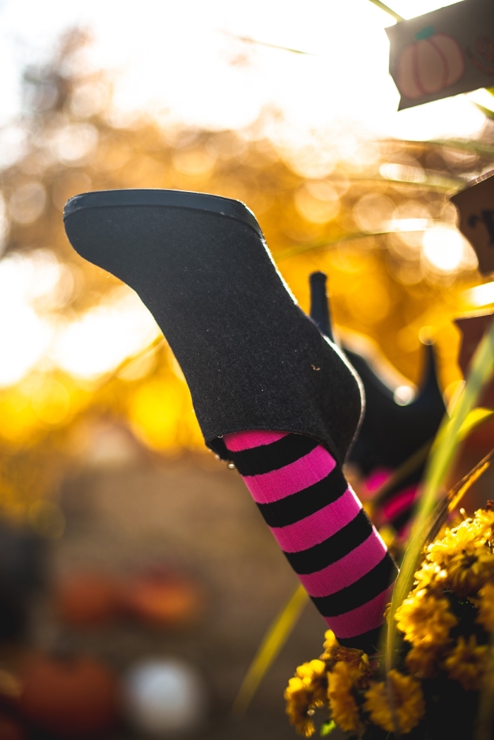 déguisement-femme-halloween-chaussures-noires-à-talons-chaussettes-rayures-rose-et-noir-sorcière-halloween-costume-lumière-soleol idée wallpaper portable pour halloween, photo Halloween avec chaussette sorcière dans la forêt et fleurs jaunes