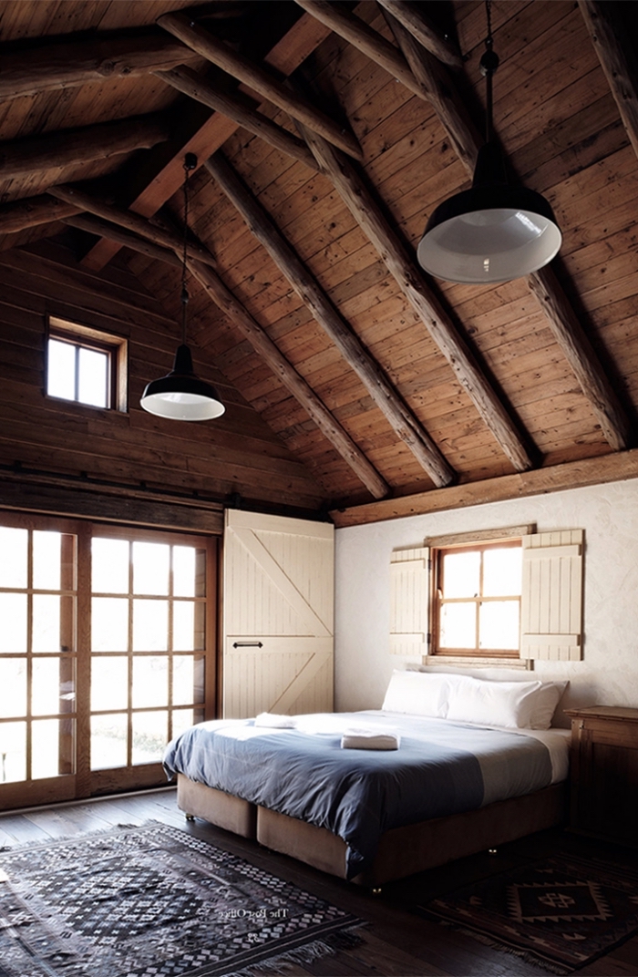 exemple de grange aménagée de style chalet, décoration chambre blanche et bois foncé au plafond haut avec sol bois foncé
