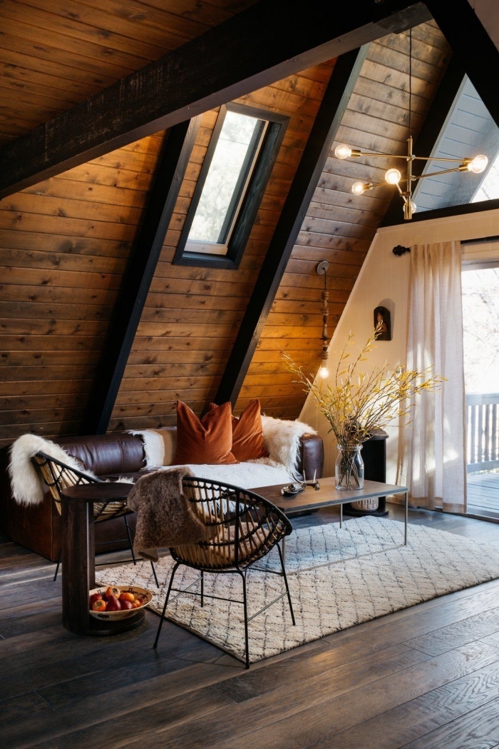 exemple de grange aménagée moderne, décoration style chalet en bois foncé avec meubles canapé cuir et table métal