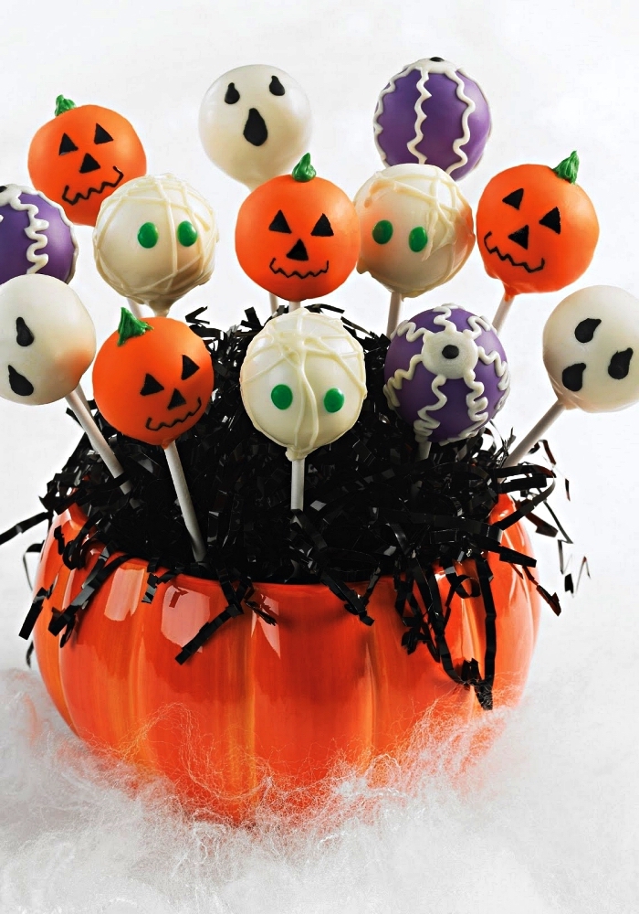 recette cake pops personnages d'halloween au glaçage coloré posés dans un bol en forme de citrouille, recettes faciles pour un apéro d'halloween