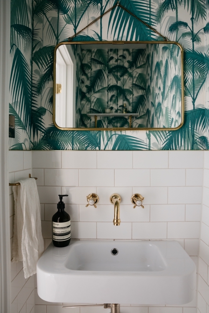 ambiance tropicale dans les toilettes, décoration pièce en blanc avec accents dorés et papier peint effet feuilles tropicales