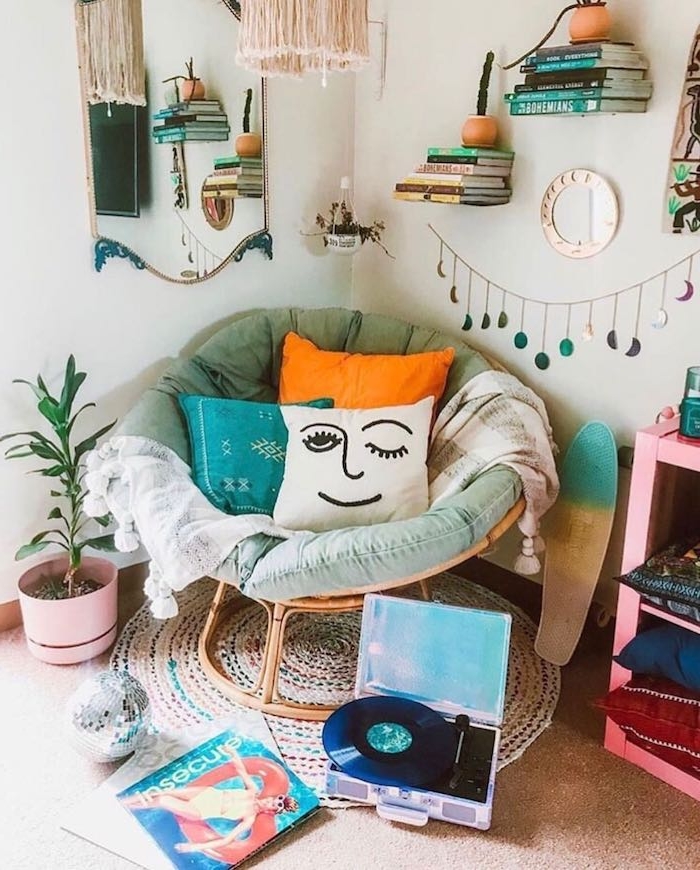coin lecture cosy en fauteuil cocooning décoré de coussins colorés, tapis rond tressé, étagères murales flottantes avec piles de livres