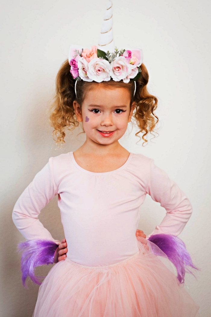 déguisement licorne fille avec jupe tutu rose et un serre-tête licorne avec fausses fleurs, maquillage de licorne fille avec petit dessin coeur violet sur la joue