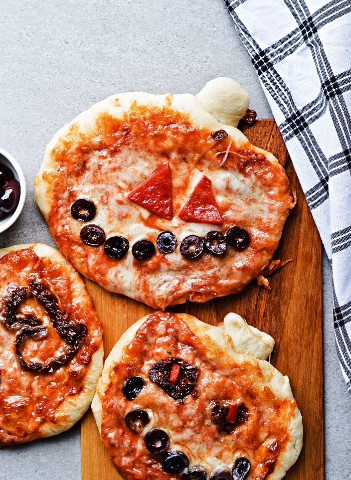 pizza halloween en forme de citrouille effrayante, mini-pizza d'halloween au fromage, tomates et olives