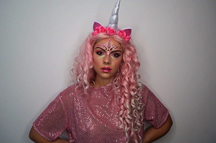maquillage d'halloween licorne avec des strass collés sur le front et dessous les yeux, déguisement de licorne avec perruque rose et serre-tête corne de licorne