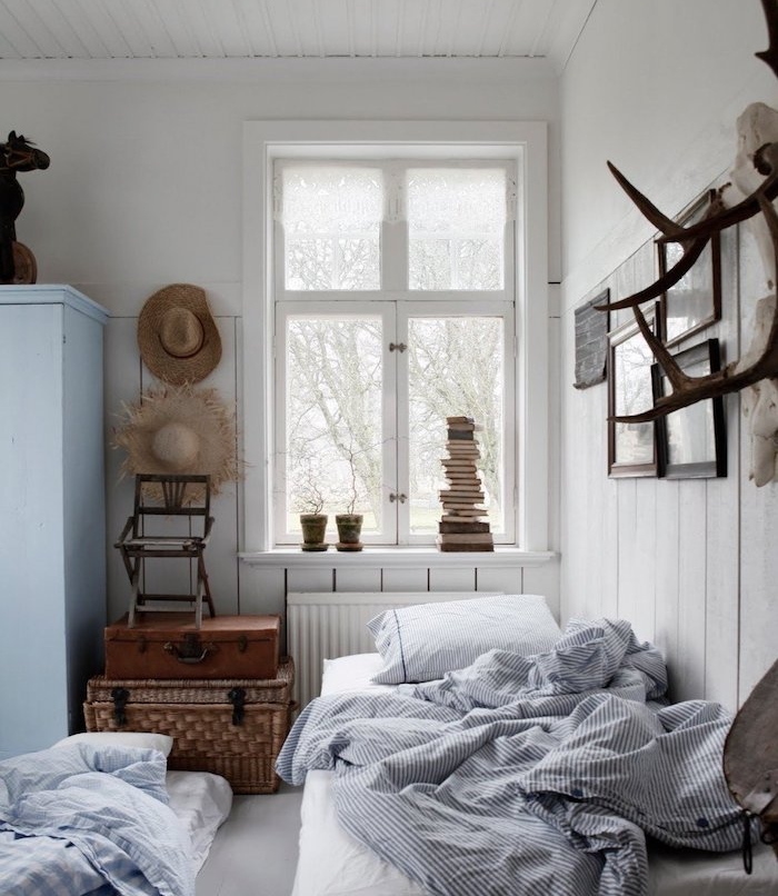 mur lambris blanc, rangement malles recuclées, linge de lit noir et blanc, armoire blanc cassé, deco chambre vintage rustique