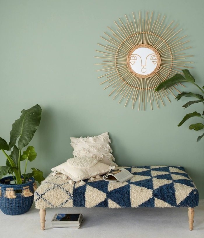déco murale avec miroir soleil rotin de Justina Blakeney, idée nid lecture cocooning avec banquette bois et accessoires en beige et bleu marine