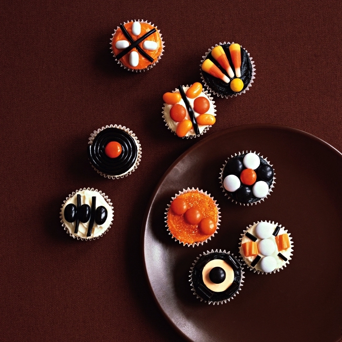 cupcakes d'halloween au glaçage orange, noir et blanc, décorés de confieseries, idée de petit gateau halloween 