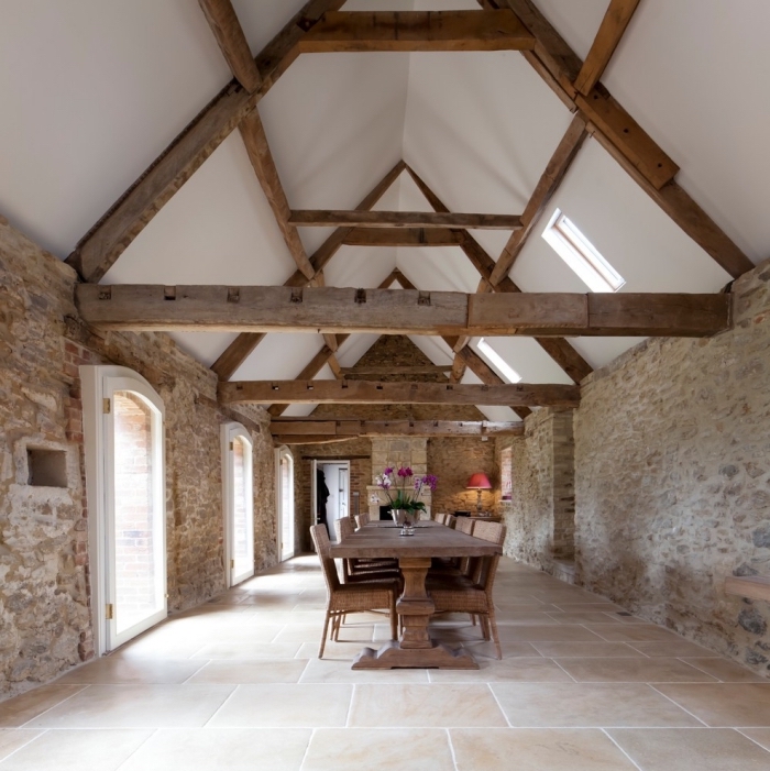 aménagement grange, design intérieur style rural aux murs pierre et poutres bois avec meubles en bois dans une salle à manger