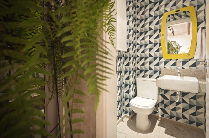 deco toilette petit espace aux murs habillées en carrelage motifs graphiques en nuances de gris et bleu avec accents jaune