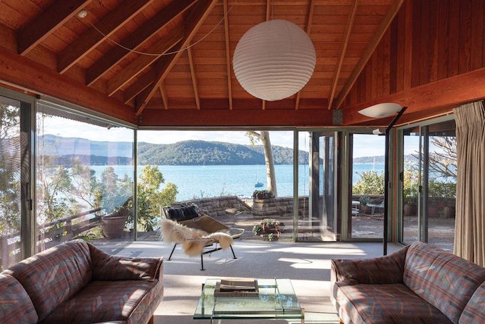 Vue magnifique de chalet au bord d'un lac, deco cocooning, deco chalet montagne cosy style nordique, deux canapés et table basse salon