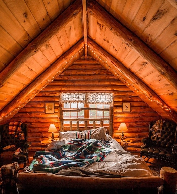 Bois intérieur décoré avec guirlandes lumineuses en haut du lit, petit chalet en bois, decoration bois maison rustique