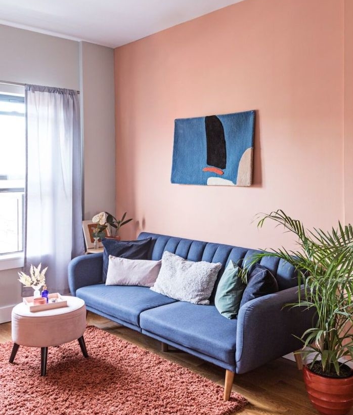 peinture couleur saumon dans un petit salon, murs accent saumon, canapé gris foncé, tapis rose foncé, table basse tabouret
