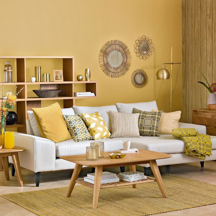 idée peinture salon jaune avec canapé blanc cassé surchargé de coussins jaune, gris et blanc, table basse bois, miroirs soleil