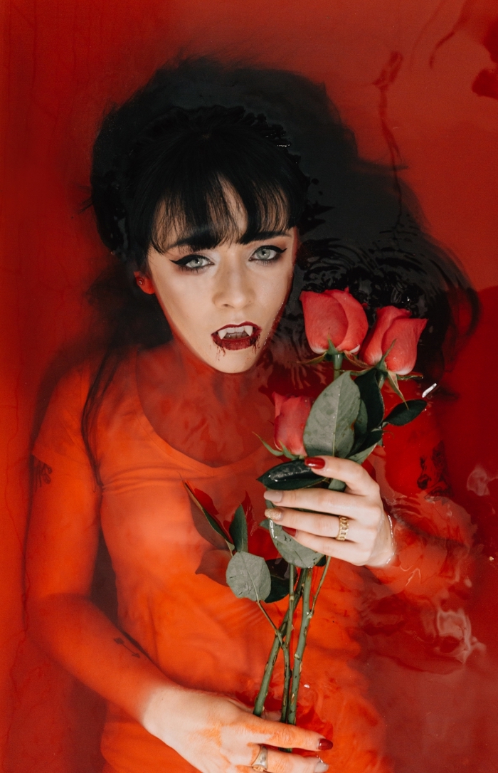 coupe-cheveux-longs-avec-frange-maquillage-rouge-à-lèvre-mat-déguisement-halloween-femme-en-vampire exemple de maquillage halloween facile façon femme vampire aux lèvres rouges avec crocs, tenue femme vampire
