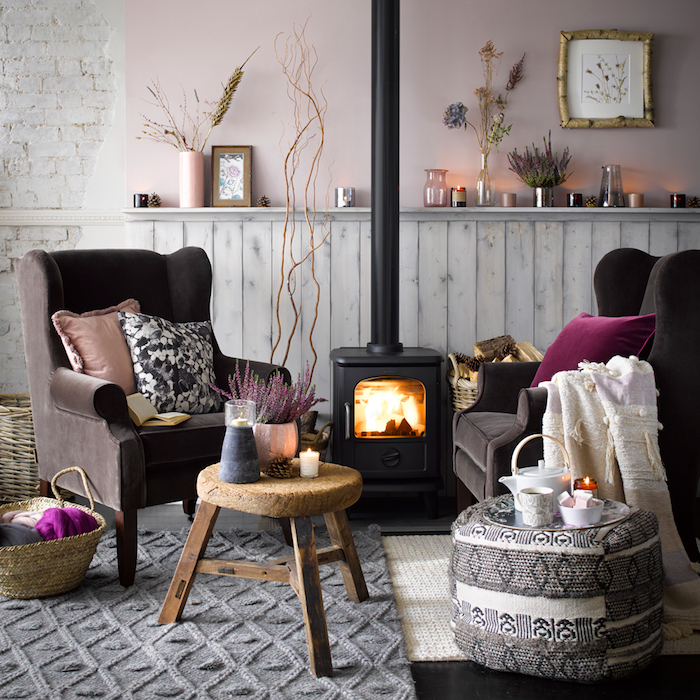 deco salon cocooning en rose clair avec fauteuils marron foncé, tapis gris tricot et pouf table noir et blanc, cheminée moderne