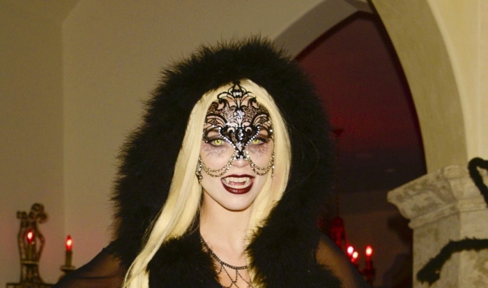 deguisement-vampire-maquillage-annalynne-mccord-capuche-faux-fur-accessoire-femme-vampire-visage-rouge-à-lèvre-foncé costume femme vampire en noir, idée déguisement halloween femme en vampire, exemple maquillage visage blanc et yeux vampire