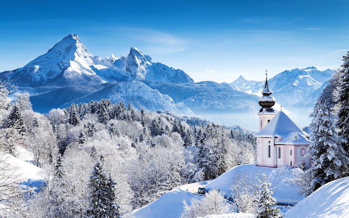 une église batiment historique bleu et rose au top d un pic de montagne enneigée, plusieurs arbres enneigés, paysage hiver